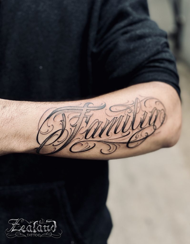 Lettering tattoo saying Blessed on the right forearm